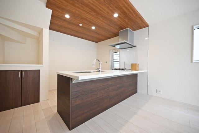 ブルーミングガーデン堀池1丁目新築一戸建│3LDK+駐車2台可(車種制限有)のキッチン|キッチン上部は折下天井を採用でデザイン性を向上させています。ダウンライトを4基採用し、作業性を確保。冷蔵庫置場横にはカウンター付収納が設けられています。