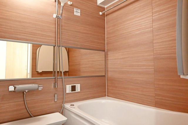 吹田ロイヤルマンションの浴室|バスルームは、光沢のある優しいブラウンのアクセントパネルが高級感を演出しています。 ミラー・小物置き場もございます。