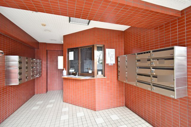 光建ハイムブリリアンス大宮公園のエントランス|陽光を反射する明るいタイル貼りのエントランスホール。集合ポストや管理人窓口が整然と並び、管理体制の良さが伺えます。防犯面でも安心感があり、住まう方を優しく迎え入れる清潔感に満ちた共用空間です。