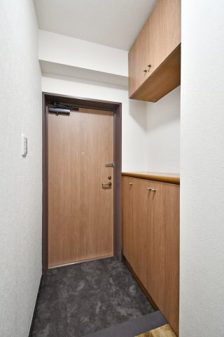 光建ハイムブリリアンス大宮公園の玄関|落ち着いた木目調の玄関扉と、上下に分かれたセパレート型のシューズボックスが機能的な玄関空間です。空間を圧迫しないデザインでありながら収納力も確保し、すっきりとした印象でゲストを迎えられます。