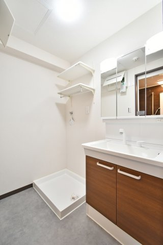 光建ハイムブリリアンス大宮公園の独立洗面台|三面鏡裏に収納を備えた、機能的なシャワー付洗面化粧台。洗濯機置場の上部には便利な可動棚も設置済み。2025年2月のリフォームで一新された、使い勝手の良いサニタリー空間で朝の支度もスムーズに整います。