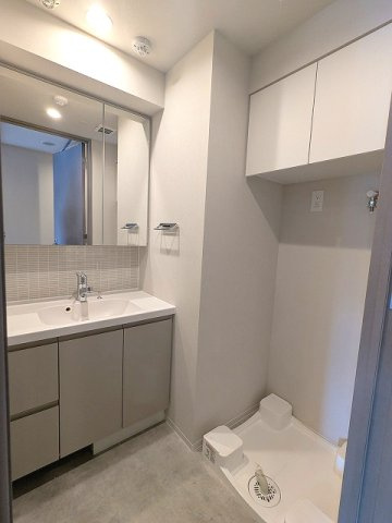 SEASON FLATS浅草六丁目の洗面所|トイレと独立した洗面脱衣室、2面鏡付ハンドシャワー付洗面台、洗面台下にはヘルスメーターストックあります、洗濯機置場は排水口のお手入れしやすい様に手前中央に配置し、足高の防水パンです