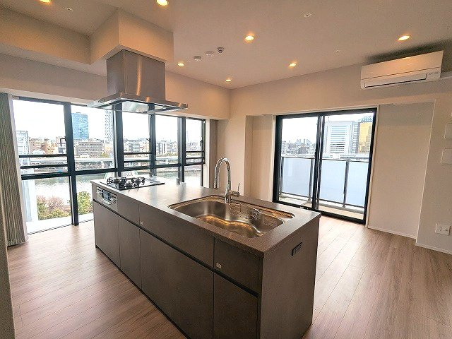 SEASON FLATS浅草六丁目のキッチン|グリル付ガス3口システムカウンターアイランドキッチン、奥まで収納しやすいスライド式の収納、瀟洒でお手入れ楽なガラストップコンロです