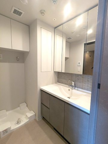 SEASON FLATS浅草六丁目の洗面所|トイレと独立した洗面脱衣室、2面鏡付ハンドシャワー付洗面台、洗面台下にはヘルスメーターストックあります、洗濯機置場は排水口のお手入れしやすい様に手前中央に配置し、足高の防水パンです