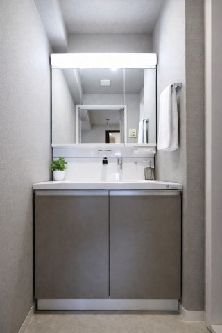 プライムコート高槻総持寺の独立洗面台|【洗面】三面鏡洗面化粧台で、朝の身支度がスムーズに進む使い勝手の良い設計。鏡の裏に収納があるため、洗面台まわりを清潔に保てる快適空間です