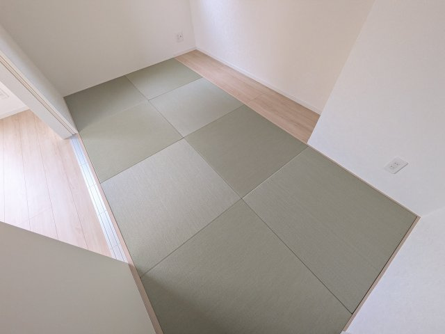 東海村村松第6　新築戸建の前面道路含む現地写真|モダンなフチなし琉球畳を採用。リビングと繋がる多目的な空間は、客間やお子様の遊び場、家事スペースとしても活躍します。