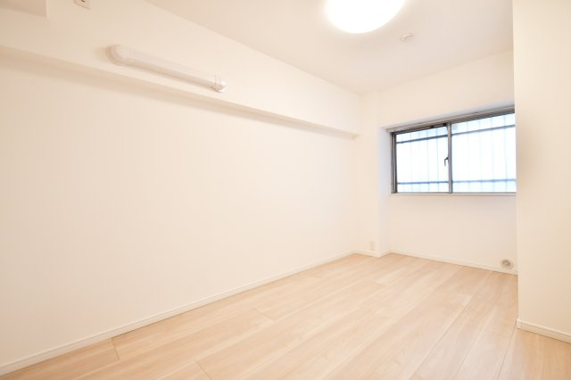 洋伸大宮マンションの洋室|静寂に包まれる、約5.6帖のプライベート空間。共用廊下側の窓からも光が入り、白を基調とした内装が明るさを引き立てます。全居室にエアコン設置が可能。集中したいワークスペースや寝室におすすめ。