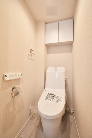 洋伸大宮マンションのトイレ|令和8年1月新規交換済、温水洗浄便座です。上部には便利な吊戸棚が付き、掃除道具やストック類もスッキリ収納可能。フロアタイルも張替済で、細部まで清潔感の行き届いた空間です。