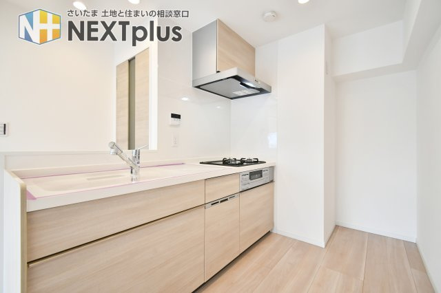 洋伸大宮マンションのキッチン|令和8年1月完工のリノベーション物件。木目調のデザインが美しいシステムキッチンは食洗機・浄水器内蔵の高性能モデルです。リビングを見渡せる対面式で、家事をしながら家族との会話も楽しめます。