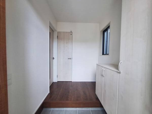 上田町3丁目1期1号棟の玄関|玄関にはシンプルで使いやすい収納スペースが備わっており明るい雰囲気です。床の切り替え部分がアクセントになっています。窓から自然光が差し込み玄関全体を爽やかにしています。