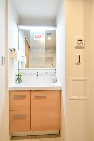 ベルヴィル大宮A棟の独立洗面台|三面鏡タイプの洗面化粧台を新設。鏡裏収納付きで、散らかりがちな家族の洗面小物も綺麗に整頓可能です。木目調のデザインが空間に温かみを与え、忙しい朝の身支度もスムーズに、気持ちよくスタートできます。