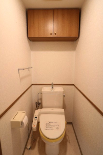 ロイヤル平針のトイレ|暖房便座付シャワートイレ。トイレットペーパーなどの消耗品をスッキリ収納できる吊戸棚がございます。