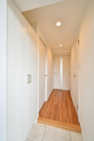 コスモ大宮日進の玄関|光沢あるフロアタイルと温もりあるフローリングのコントラストが美しい廊下。全室クロス貼替済みの明るい空間は、帰宅するたびにリフレッシュできる開放感に満ちています。