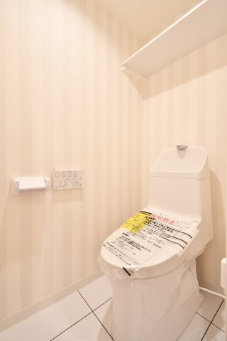 コスモ大宮日進のトイレ|令和8年1月新規交換済。ストライプ柄のアクセントクロスが洗練された空間を演出します。温水洗浄便座や便利な吊戸棚付き。毎日使う場所だからこそ、心地よさにこだわりました。