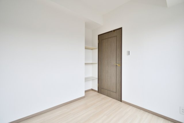 ライオンズマンション大宮大和田第2の洋室|洋室②：新調されたフローリングとクロスが美しい洋室。デッドスペースを活かした固定棚付きで、お気に入りの小物を飾るなど自分好みの空間演出が可能です。モダンな建具が映える、洗練された個室空間。