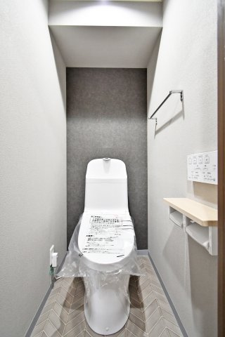 ライオンズマンション大宮大和田第2のトイレ|トイレ本体を新規交換。モダンなアクセントクロスとヘリンボーン調の床材が、洗練された個室空間を演出します。温水洗浄便座付きで、毎日を清潔・快適にお過ごしいただけます。