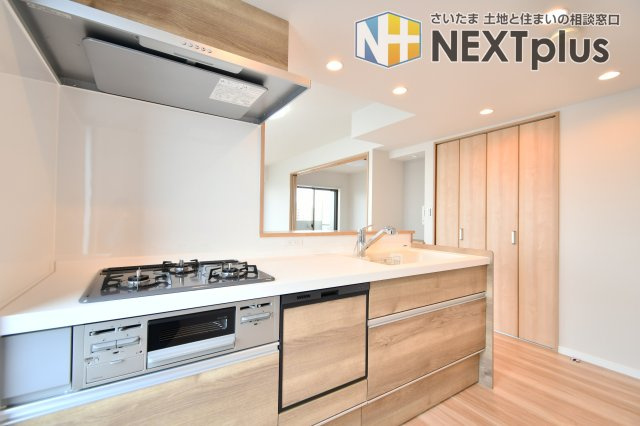 大宮パーク・ホームズのキッチン|料理中も家族やペットを見守れる対面キッチン。新規交換予定のシステムキッチンには、忙しい共働き世帯を助ける食洗機付き。木目調の美しいパネルが、毎日の家事を楽しく彩ります 。