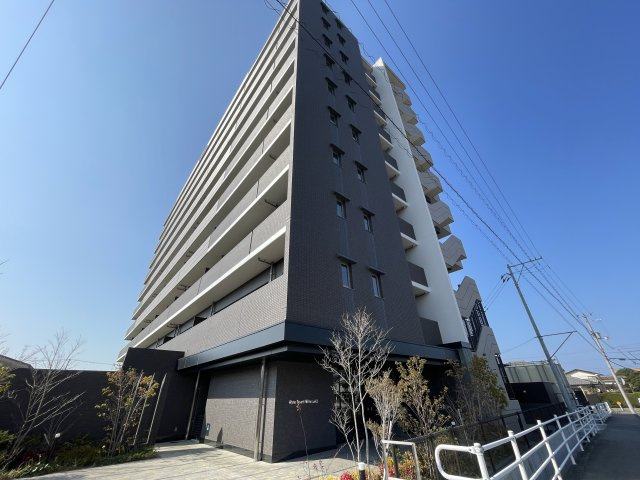 アルファスマート新居浜駅Ⅱの外観|重厚感と高級感を兼ね備えた１０階建てのフォルム。バルコニーのガラス手摺が空を映し出し、スタイリッシュな印象を与えます。セキュリティラインが明確で、住まう人の安全と安心を守る堅牢な外観デザインです。