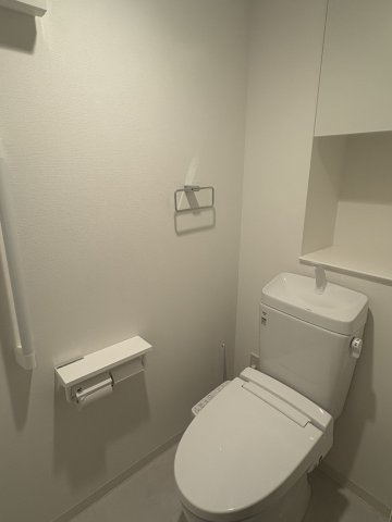 アルファスマート新居浜駅Ⅱのトイレ|温水洗浄便座付きの清潔なトイレ。上部には棚が設置されており、トイレットペーパーや掃除用具をすっきりと収納できます。シンプルでモダンなデザインは落ち着きがあり、来客時にも好印象を与える清潔な空間です。