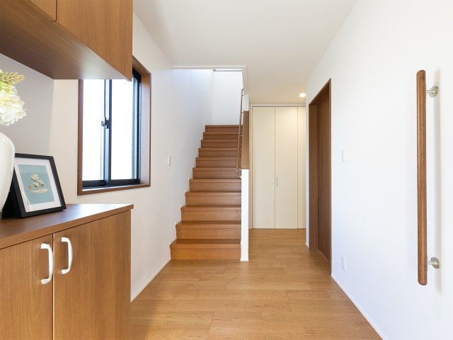 福島市笹谷の玄関|新規交換したシューズボックスと明るいクロスが迎える玄関。手すり付きの階段やゆとりある動線が魅力です。