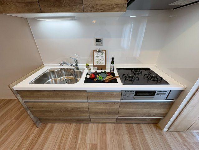 境谷西第2住宅団地16棟のキッチン|木目調のシステムキッチン。3つ口ガスコンロは同時調理に重宝します◎