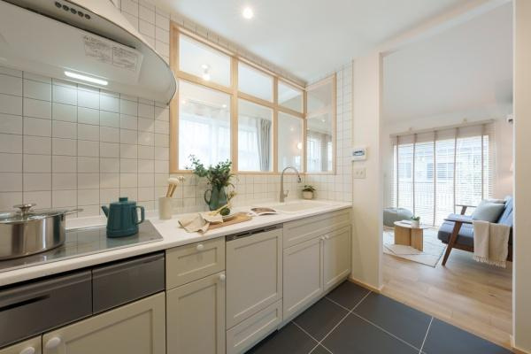 三佐　BERSAのキッチン|タイル張りで明るい印象のキッチンです。収納スペースが充実しています。窓からの自然光が差し込み室内を明るく保ちます。グレーの床タイルが落ち着いた雰囲気を演出しています。