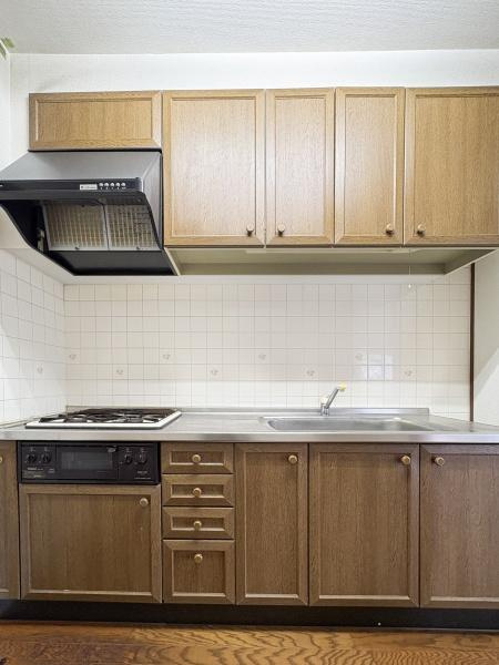 パークサイドおおみちのキッチン|木目調のデザインが温かみを感じさせるキッチンです。収納が豊富ですっきりとした空間が確保されています。タイル張りの壁面はお手入れがしやすく換気扇も設置されています。