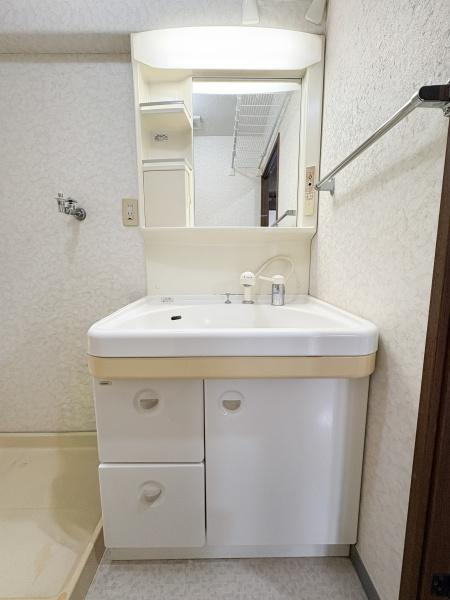 パークサイドおおみちの独立洗面台|シンプルなデザインの洗面台はお手入れがしやすいです。収納スペースもしっかり用意されています。ミラーが付いていて身だしなみチェックにも便利です。タオル掛けが壁に設置されているのもポイントです。