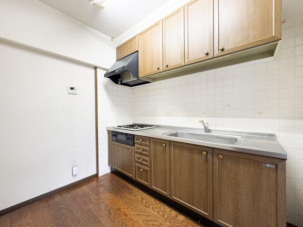 パークサイドおおみちのキッチン|木目調のキャビネットが印象的なキッチンです。シンクとコンロが横並びで使いやすいレイアウトです。収納が豊富で整理整頓がしやすい印象です。広々とした作業スペースが確保されています。