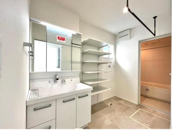 横尾　9号地の独立洗面台|広々とした洗面台と収納棚が設置されており室内がすっきりとした印象です。明るい空間設計で毎日の支度がしやすく感じられます。洗面所と浴室が隣接しているため動線も良好です。