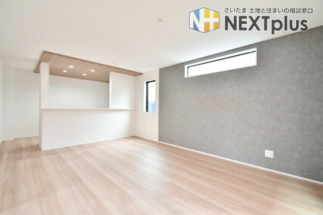 伊奈町小室10期　全1棟の居間・リビング|キッチンに立ちながらリビング全体を見渡せる、共働き世帯に嬉しい設計。木目調の天井が、空間に奥行きと温もりを与えます。家族がどこにいても気配を感じられる、一体感のある暮らしをここから始めませんか。