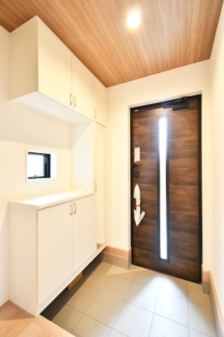 伊奈町小室10期　全1棟の玄関|重厚感漂う玄関ドアと温もりある木目調天井が、洗練された日常を演出します。大型のシューズボックス付きで、家族全員の靴もスッキリ収納。小窓からの自然光が明るく、清潔感あふれる空間がゲストを優しく迎えます。