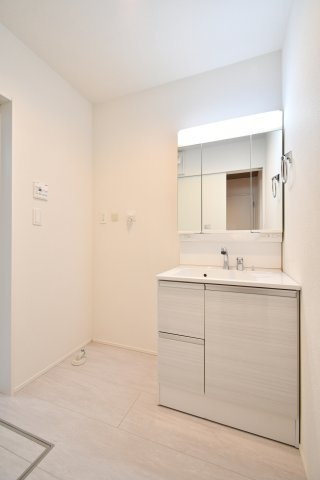 伊奈町小室10期　全1棟の独立洗面台|鏡裏に小物を隠せる3面鏡は、生活感を抑えつつ収納力を確保。シャワー付き水栓で日々のお手入れも簡単。横には洗濯機置場があり、脱衣・洗濯・洗面がスムーズに完結する効率的な家事動線を実現しました。