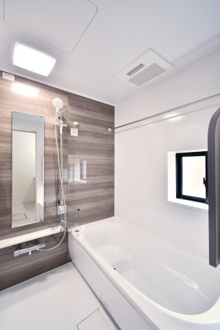 伊奈町小室10期　全1棟の浴室|落ち着いた木目調のアクセントパネルがリラックスタイムを演出。雨の日の洗濯に重宝する浴室乾燥機や、自然光を取り込む窓付き。広々としたバスタブで、至福のバスタイムをお楽しみください。