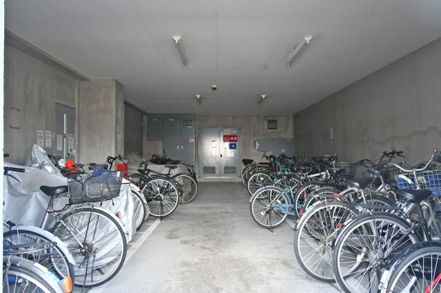 クレセント東鷲宮の駐輪場|敷地内の駐輪場は屋根のある共用スペース内に設けられており、自転車をまとめて置ける配置です。雨天時の利用や日常の出し入れもしやすそうで、使用条件などの詳細は現地でご確認いただけます。