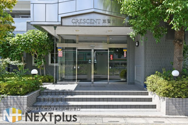 クレセント東鷲宮のエントランス|植栽に彩られたエントランスは、建物の顔として落ち着いた印象です。前面から出入りしやすい配置で、共用部の雰囲気や管理状態も現地で確認しやすい写真となっています。