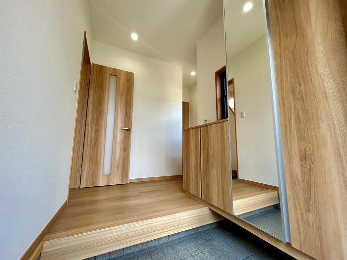 松山市西長戸　再生住宅の玄関|扉を開けると、リフォームされた明るい空間が家族を優しく出迎える。TVモニター付インターホンで防犯性も向上。広めの玄関スペースは、ベビーカーやお出かけの道具も置きやすく、毎日を快適に。