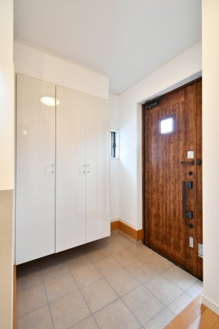 伊奈町西小針1丁目の玄関|重厚感ある木目調の玄関ドアが、家族を温かく迎えます。大容量のフロートタイプ靴箱は、玄関をスッキリ見せつつ掃除も楽々。小窓からの自然光が明るい空間を演出し、毎日の出掛けを心地よいものに変えてくれます。