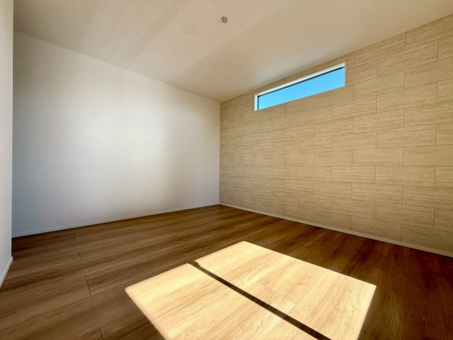 香美市土佐山田町宝町2期5棟 5号棟の洋室|高窓から柔らかな光が広がる落ち着きの洋室。ナチュラルなアクセント壁が上質な雰囲気を演出します