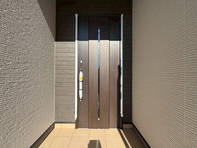 香美市土佐山田町宝町2期5棟 5号棟の玄関|落ち着いた木目調の玄関ドアが家の顔に。深いアプローチで雨の日も濡れにくく、快適に出入りできます