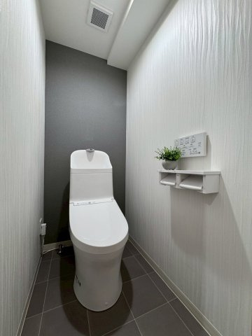 寝屋川サンハイツA棟のトイレ|トイレはグレーのクロスで落ち着いた色味です。温水洗浄便座付きです。