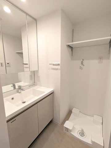 RETERRACE三ノ輪ウエストの洗面所|トイレと独立した洗面脱衣室、三面鏡付洗面台、洗濯機置場は排水口のお手入れしやすい様に手前中央に配置し、足高の防水パンです