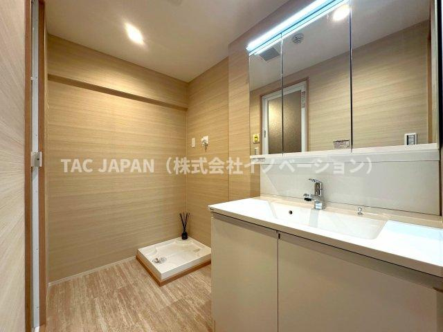 目白ガーデニアの洗面所|大型の洗濯機を置いても余裕が感じられる脱衣スペース。豊富な収納を誇るお洒落な洗面ユニットはお手入れ楽々シームレス仕様です。