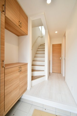 上尾市泉台2丁目2期　全1棟の玄関|温かみのある木目調の建具とホワイト基調の内装が、家族を優しく迎えます。廊下まで一体感のあるデザインは空間を広く見せる効果も。階段横のデッドスペースまで活用した収納力にご注目！