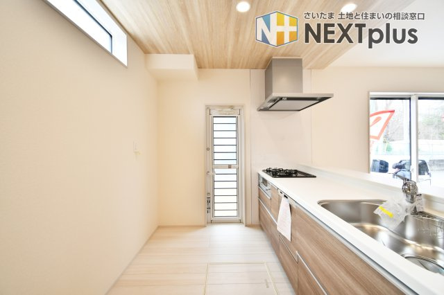 上尾市泉台2丁目2期　全1棟のキッチン|ゴミ出しに便利な勝手口や、手元を照らす採光窓付き。木目調のポップアップ天井が空間をスタイリッシュに演出します。機能性とデザインが共存する、家事が楽しくなる特等席です。