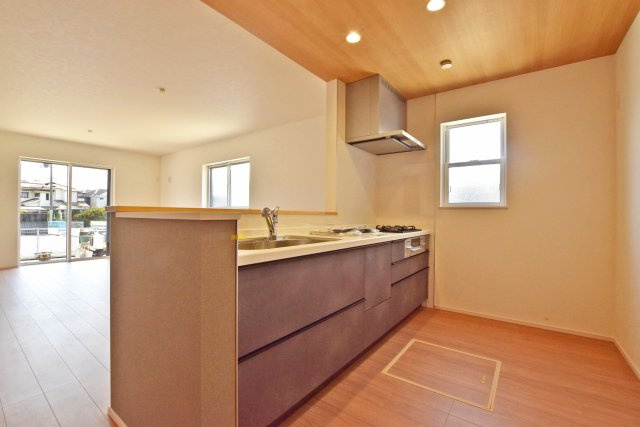 ファーストタウン伊丹市堀池2丁目新築一戸建て全2区画│2SLDK+駐車1台可のキッチン|1階キッチンユニット越しに撮影した内観写真です。 キッチンに小窓が設けており、調理で煙だらけになってもすぐに換気できます。
