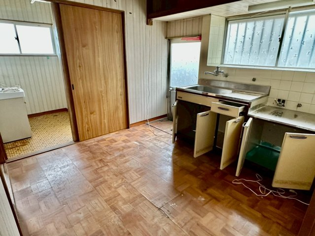 寿町　中古戸建のキッチン|窓から自然光が入る明るいキッチンです。勝手口を利用すれば、お買い物帰りの荷物搬入もスムーズに行えます。日々の料理を効率よく進められるよう、自分好みの収納棚を配置して使い勝手を高めることも可能です。