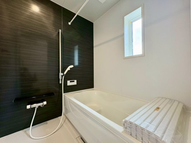 香美市土佐山田町東本町第1　1号棟新築戸建ての浴室|落ち着きあるアクセントパネルが映えるバスルーム。ゆったり浴槽と窓付き設計で、毎日のバスタイムを快適に