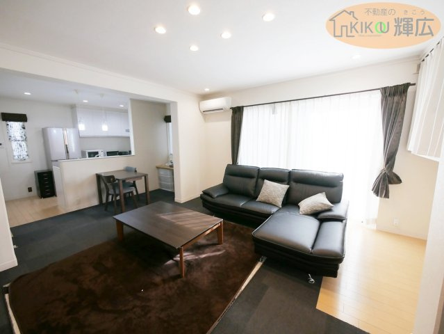 【居間・リビング】 | 姫路市大塩町汐咲 中古戸建 | 白を基調とした内装に、シックな黒の家具が映える洗練されたリビング。大きな窓からは豊かな採光が降り注ぎ、開放感あふれる空間を演出しています。