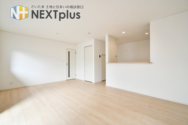 伊奈町本町第3　全2棟　1号棟の居間・リビング|キッチンからリビング全体を見渡せる安心の設計。便利なリビング収納を備えており、掃除道具や日用品をスマートに片付けられます。白壁とナチュラルな床材が、どんな家具とも調和する洗練された空間を演出します。